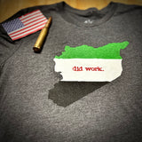 Gray t-shirt with a graphic design of a green and white flag with 'did work.' text, an American flag, and a bullet on a wooden surface.